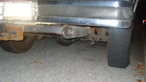 1988 Ford Bronco - The rear underside of a vehicle reveals its exhaust system and rear tire.