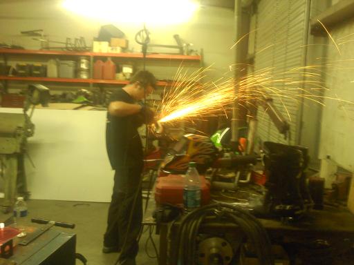 Man grinding metal, sparks flying in workshop