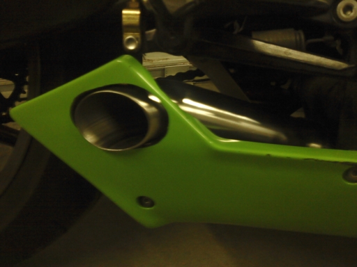 Close-up of a green motorcycle fairing with an exhaust pipe visible