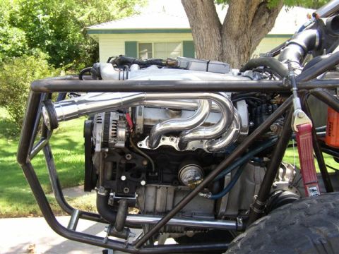 1993 Ford Taurus - Close-up of a custom engine bay with chrome exhaust headers and a protective roll cage.