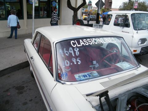 1967 Ford Fairlane - A white sedan with a red interior is parked next to a white van on a street.