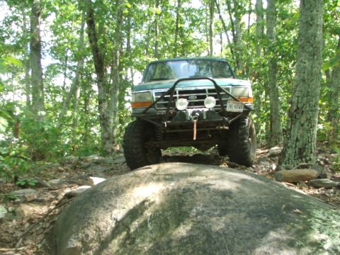 1996 Ford Bronco - Modified Ford Bronco navigating a rocky trail in a forest.