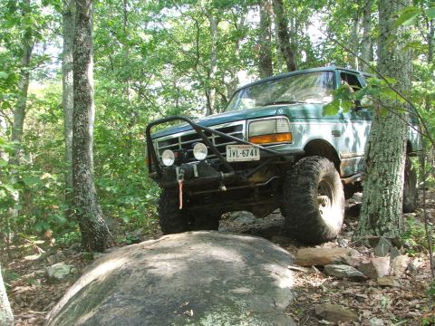 1996 Ford Bronco - This 1996 Ford Bronco navigates a challenging off-road path through a wooded area.