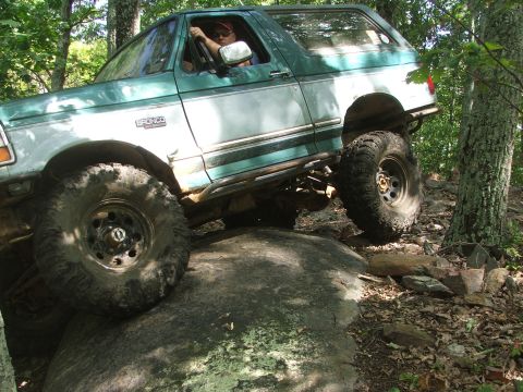 1996 Ford Bronco - This 1996 Ford Bronco is shown tackling a challenging off-road obstacle on a wooded trail.
