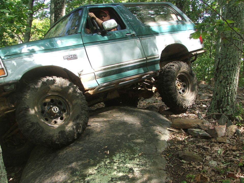 Green and white 1996 Ford Bronco navigating a rocky trail