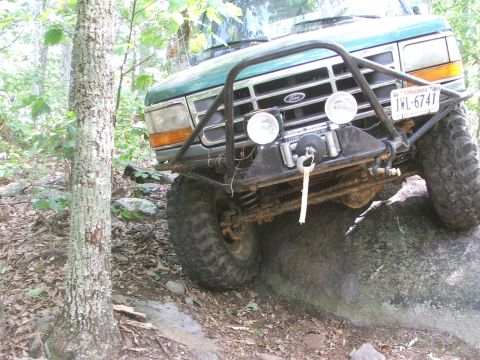 1996 Ford Bronco - Ford Bronco tackling an off-road obstacle with its front tire on a large rock.