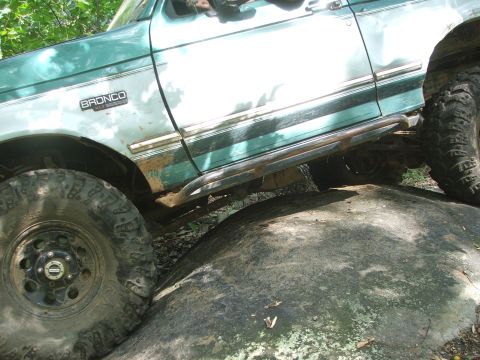 1996 Ford Bronco - A green Ford Bronco navigates a rocky trail, showing its off-road capabilities.