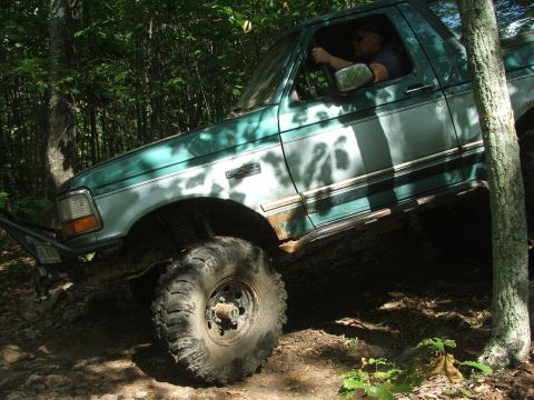 1996 Ford Bronco - 1996 Ford Bronco tackling rough terrain on a forest path.