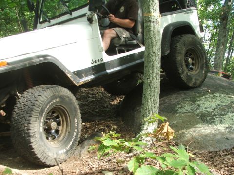 1996 Ford Bronco - A white Jeep Wrangler navigates a rocky trail, demonstrating its off-road capabilities.