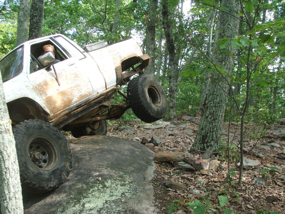White off-road SUV climbing a rock face