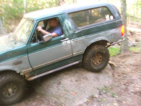 1996 Ford Bronco - 1996 Ford Bronco navigating an off-road trail in a wooded area.