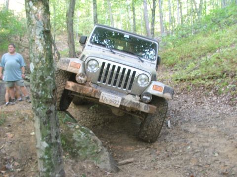 1996 Ford Bronco - A Jeep Wrangler navigates a challenging off-road trail, with a bystander observing the action.