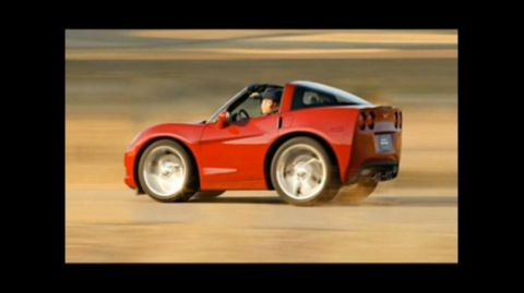 2000 Mercury Grand Marquis - A red sports car with exaggerated wheels kicks up dust as it drives across a barren landscape.