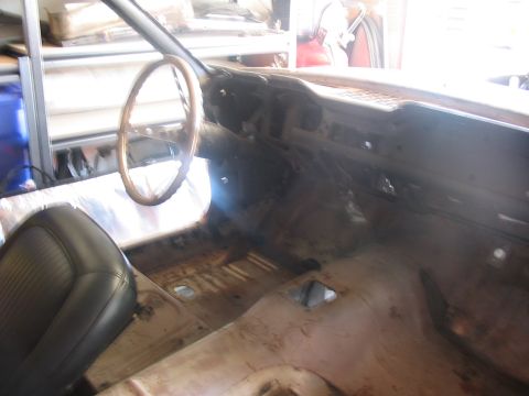 1968 Ford Mustang - The interior of a car is shown with the floor stripped and dashboard exposed, indicating a restoration project.