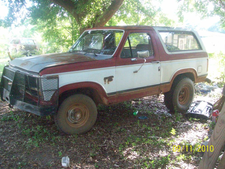1980s Ford Bronco with a brush guard and two-tone paint, parked outdoors
