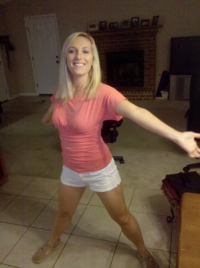 Woman in pink shirt and white shorts posing indoors