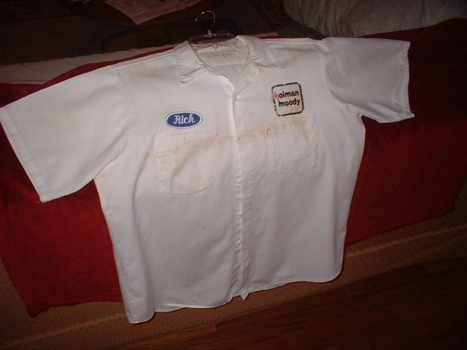 White work shirt with 'Rick' and 'holman moody' patches, stained, on a hanger