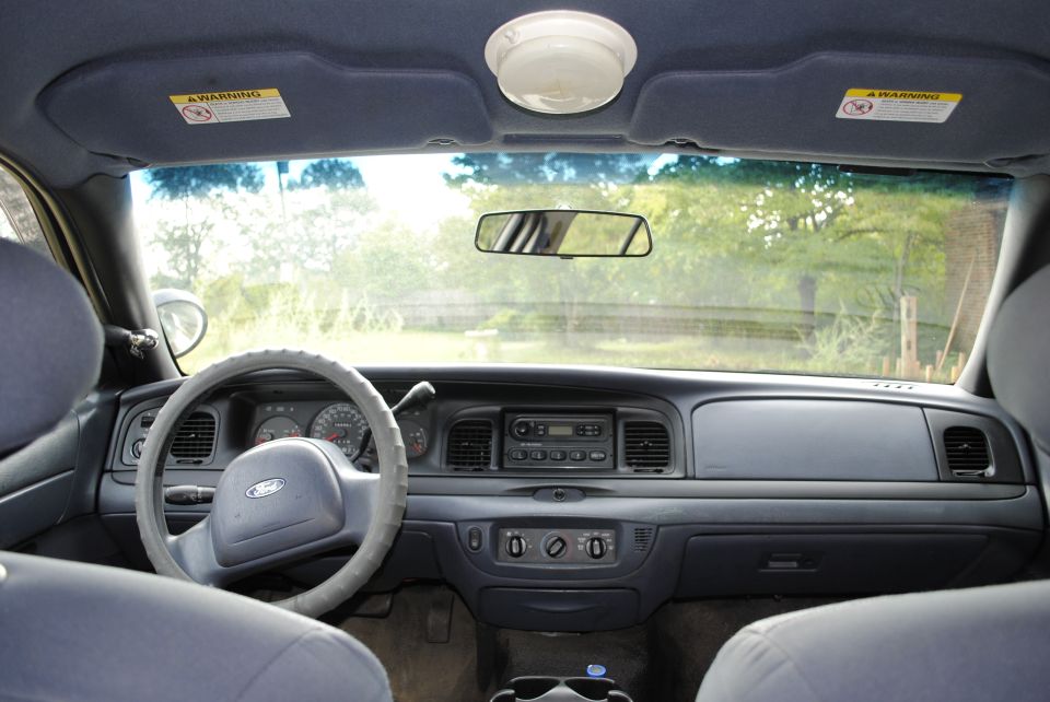 Car dashboard with steering wheel, radio, and air vents. Sun visors are up