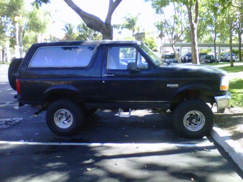 1995 Ford Bronco - This 1995 Ford Bronco is seen from the side, parked in a lot with a spare tire mounted on the back.
