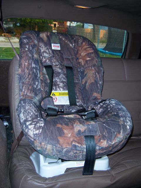 1996 Ford Bronco - Child seat with camouflage cover is secured in the back seat of a vehicle.