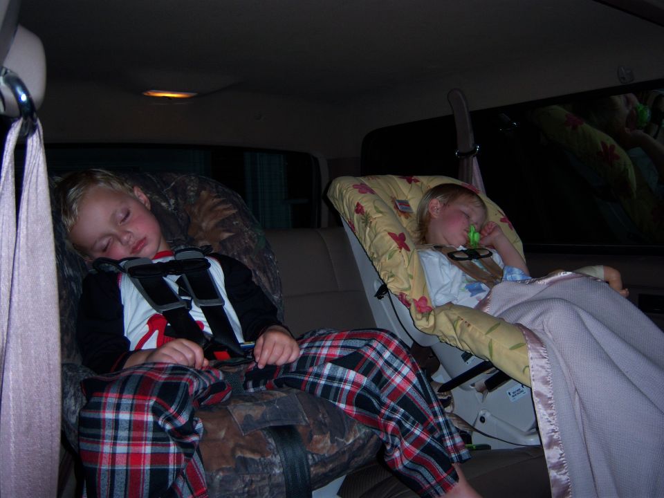 Two kids asleep in car seats in the back of a vehicle