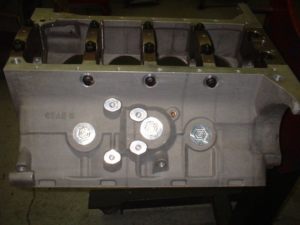 Bare Ford V8 engine block with C5AE H casting number and main caps installed, on a stand