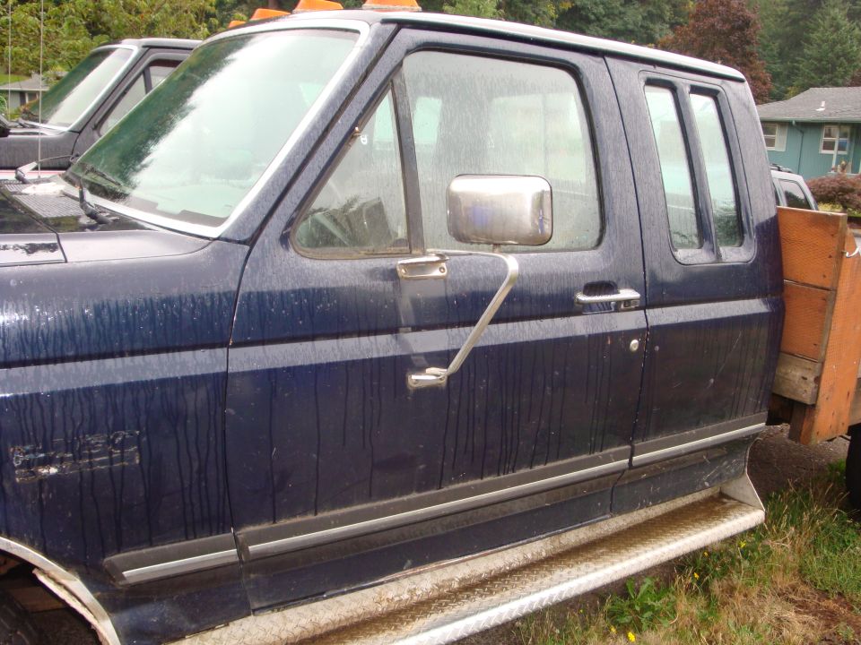 Dark blue pickup truck side view, showing the doors and a flatbed. The truck appears to be from the late 1980s
