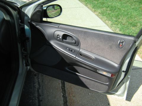 1988 Mercury Grand Marquis - Interior view of an open passenger-side front door on a silver sedan, showing the gray two-tone door panel with cloth insert, molded armres…