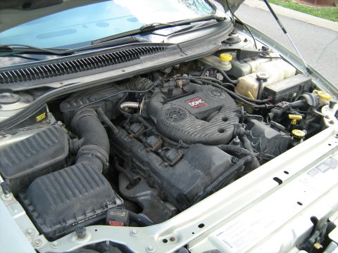 1988 Mercury Grand Marquis - Overhead view into the engine bay of a silver sedan, showing a transverse Chrysler 24-valve DOHC V6 with black plastic engine cover, coil p…