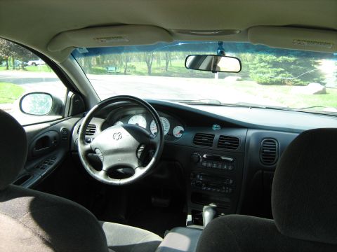 1988 Mercury Grand Marquis - Interior view from the rear seat of a Dodge sedan looking forward at the gray dashboard, four-spoke airbag steering wheel with the ram's-he…
