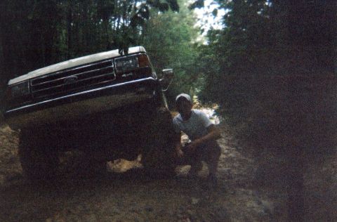 1990 Ford Bronco - A man kneels beside a 1990 Ford Bronco during a flex test with sway bars.