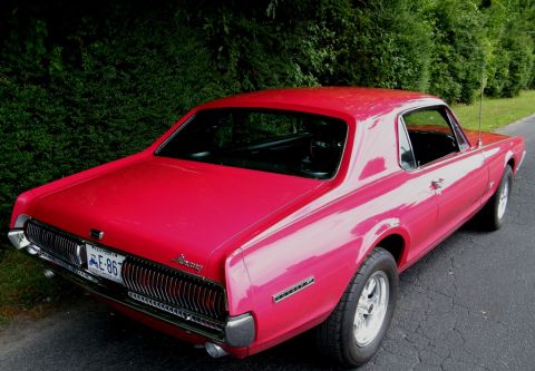 1967 Mercury Cougar - Rear view of a bright red 1967 Mercury Cougar parked on an asphalt road.