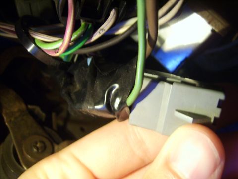 1988 Ford Crown Victoria LTD - A hand holds a gray wiring harness connector with multiple wires, including green and purple, visible.