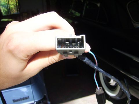 1988 Ford Crown Victoria LTD - Close-up of a car's electrical connector being held by a hand.