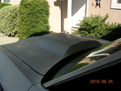 1972 Ford Ranchero - A car hood with a prominent scoop is visible, with a house and bushes in the background.