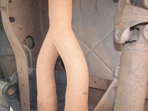1995 Ford Bronco - The underside of a vehicle reveals a Y-shaped exhaust pipe and a driveshaft, with some visible text on the exhaust.
