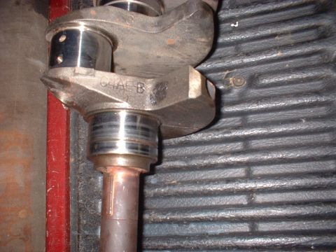 1964 Ford Galaxie - Close-up of a crankshaft part, likely from an engine, with visible casting marks and bearing surfaces.