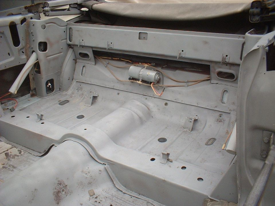 Car interior stripped down, showing floor pan and seat mounts