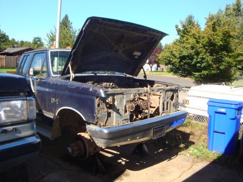 1989 Ford Bronco - A dark blue Ford Bronco/F-series with its front clip torn down, hood raised and fenders, grille and core support removed to expose the engi…