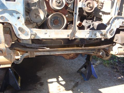 1989 Ford Bronco - Low front-end shot of a truck on blue jack stands with the grille, bumper and radiator stripped away, showing the white radiator support, f…