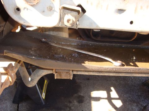 1989 Ford Bronco - Close-up of a truck's boxed frame rail with a fabricated steel brace or motor-mount tie-in tack-welded diagonally across it, shot from belo…