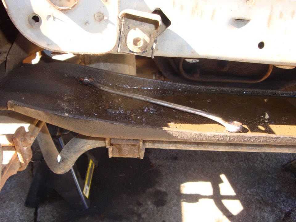 Steel brace tack-welded across a truck frame rail, viewed from underneath with a jack stand