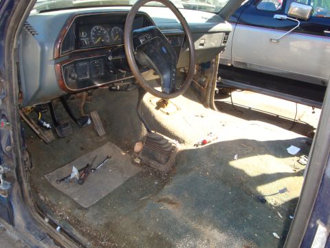 1989 Ford Bronco - The interior of a 1989 Ford Bronco shows a manual transmission and a worn dashboard, with another vehicle visible outside.