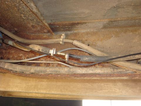 1989 Ford Bronco - Close-up of the undercarriage showing various lines and rusty metal components.