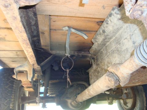 1989 Ford Bronco - Underside view of a truck's drivetrain, showing the drive shaft and rear differential, with a makeshift hanging object.