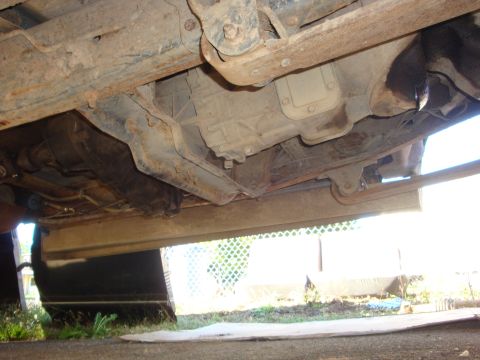 1989 Ford Bronco - The underside of a vehicle, revealing the transmission and frame, is captured from a low angle.