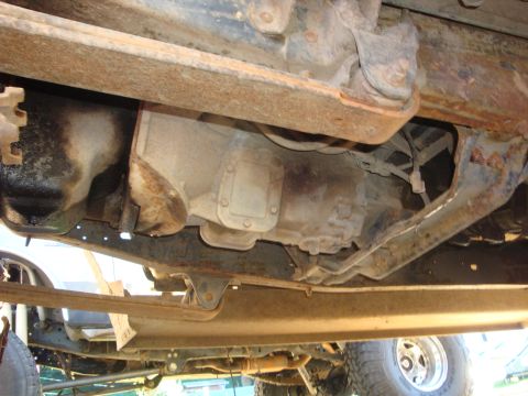 1989 Ford Bronco - Underside view of a truck's transmission and suspension components, showing rust and wear.
