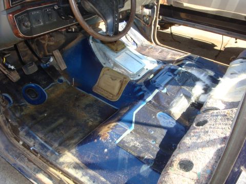 1989 Ford Bronco - Stripped interior of a truck with carpet, seats and center console removed, exposing a blue-painted floor pan with the transmission tunnel…