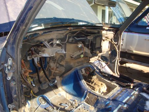 1989 Ford Bronco - Gutted truck interior with the dash pad, seats and carpet removed, showing the bare blue floor pan, transmission tunnel with shifter openin…