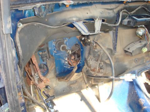 1989 Ford Bronco - Stripped driver's-side interior of a blue Ford truck with the dash pad, carpet and steering column removed, exposing the bare blue firewall…